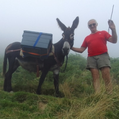 Portage par un âne en montagne pour des pécheurs avec un anier qui l'accompagne.
